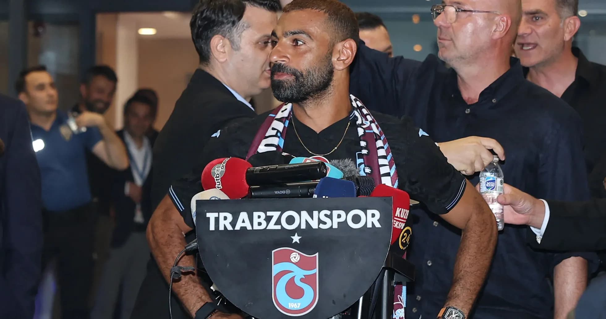 Jugador en conferencia de prensa con micrófonos y bufanda