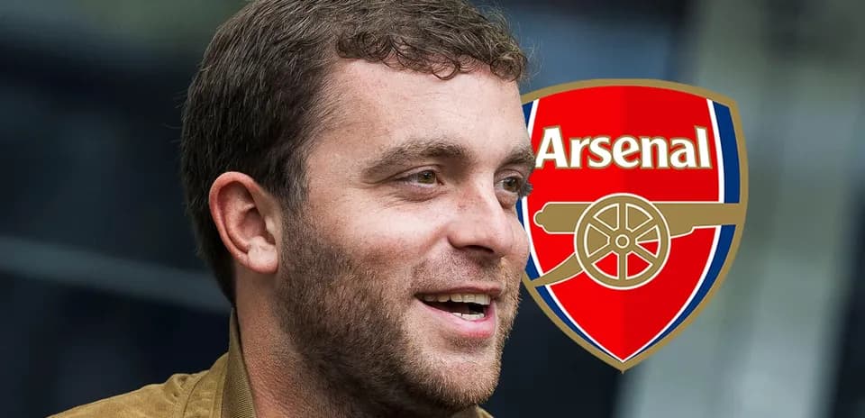 Hombre sonriendo junto al escudo de Arsenal