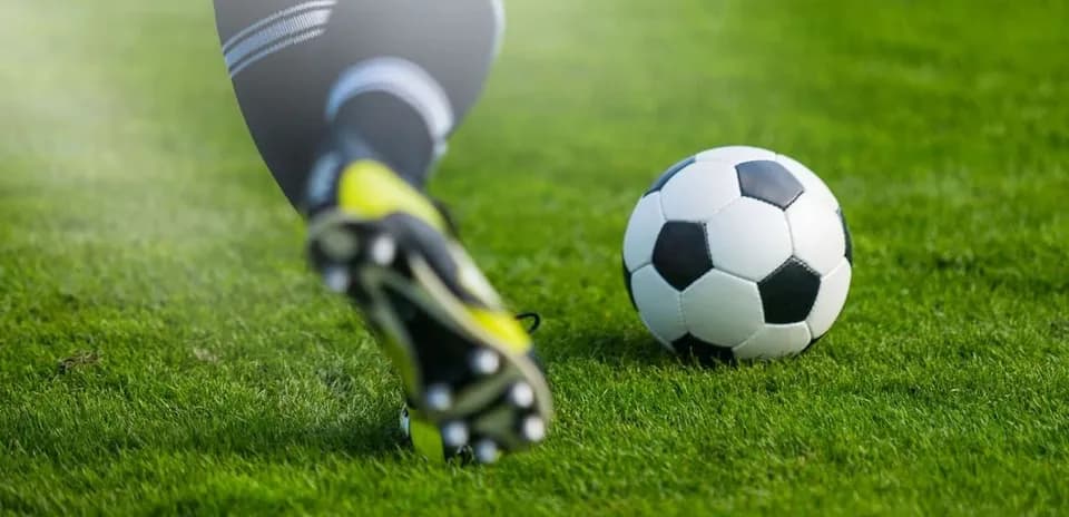 Jugador pateando un balón de fútbol en césped