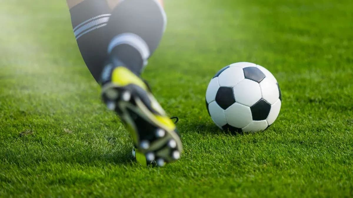 Jugador pateando un balón de fútbol en césped