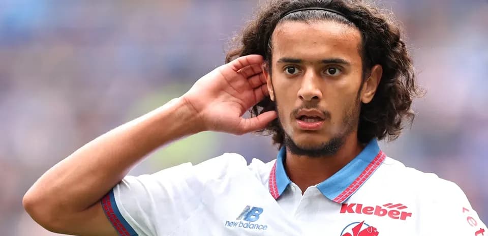 Jugador con cabello rizado señalando su oído