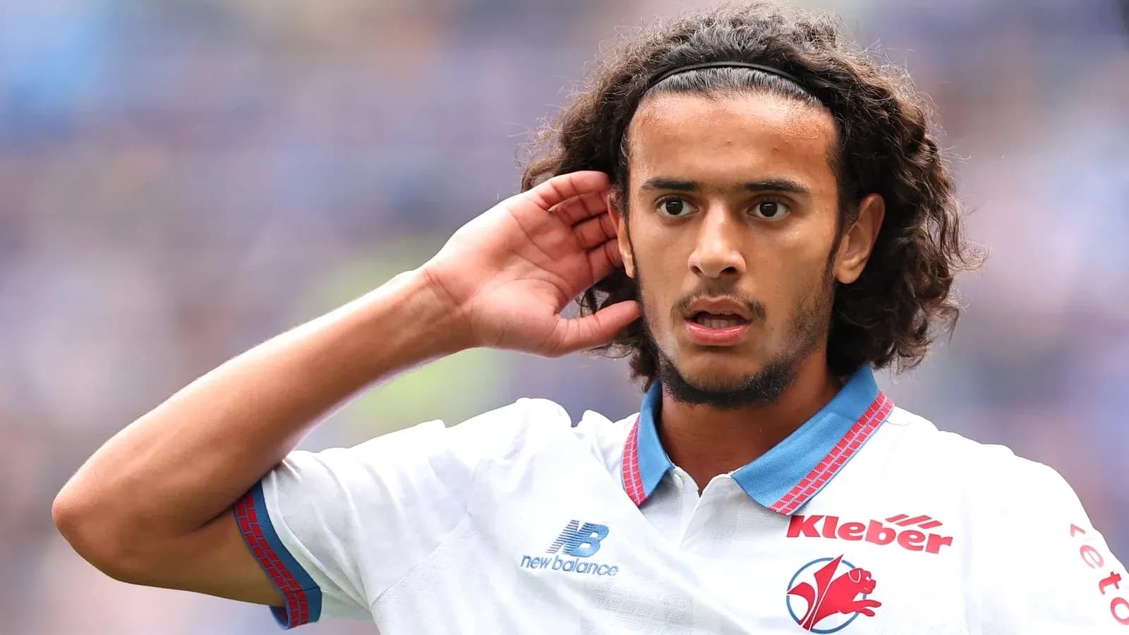 Jugador con cabello rizado señalando su oído