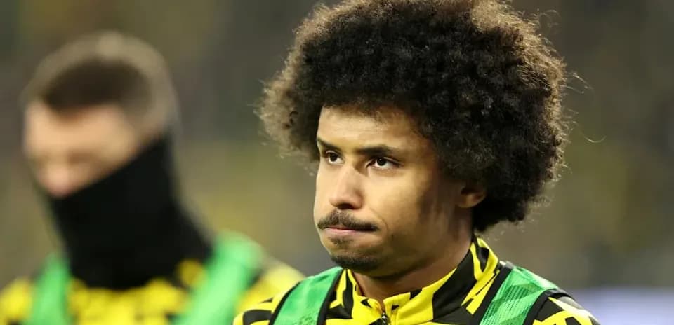 Jugador de pie en el banquillo con uniforme amarillo