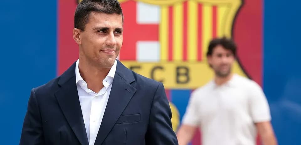 Jugador sonriendo frente al escudo del FC Barcelona