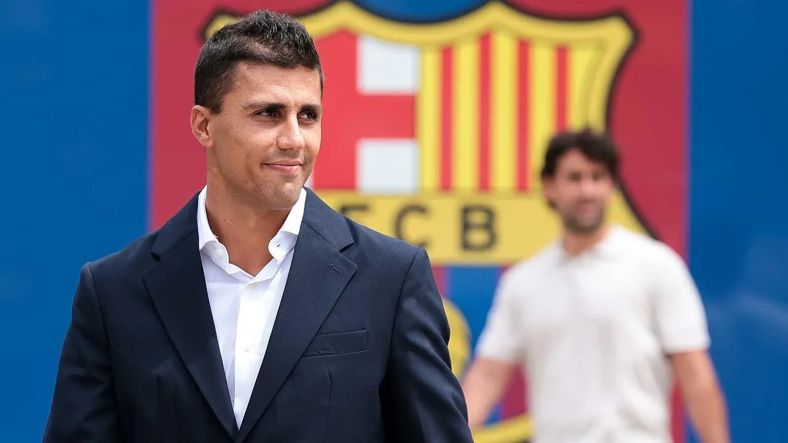 Jugador sonriendo frente al escudo del FC Barcelona