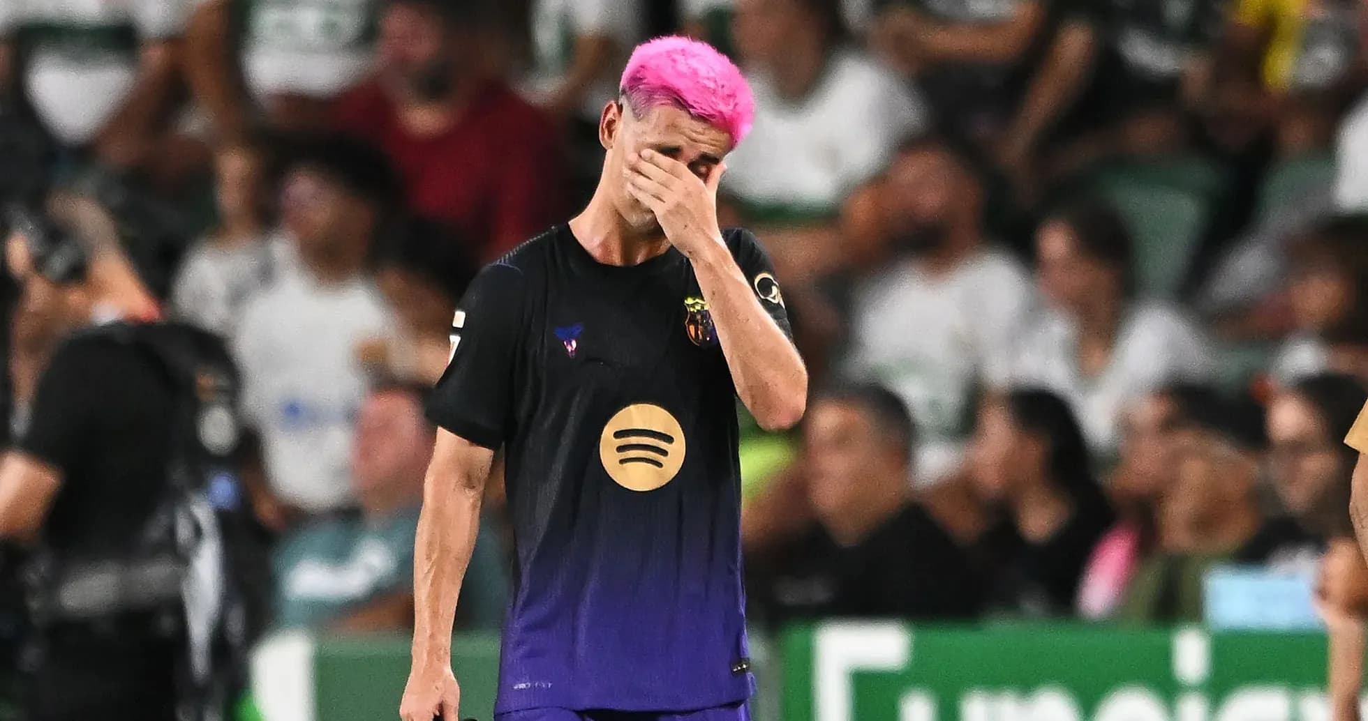 Jugador de fútbol con cabello rosa, cubriéndose la cara Jugador de fútbol con cabello rosa, cubriéndose la cara