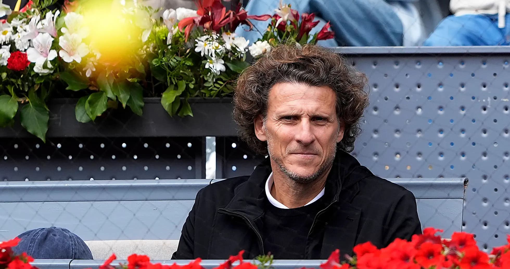 Hombre sentado entre flores en un evento de tenis Hombre sentado entre flores en un evento de tenis