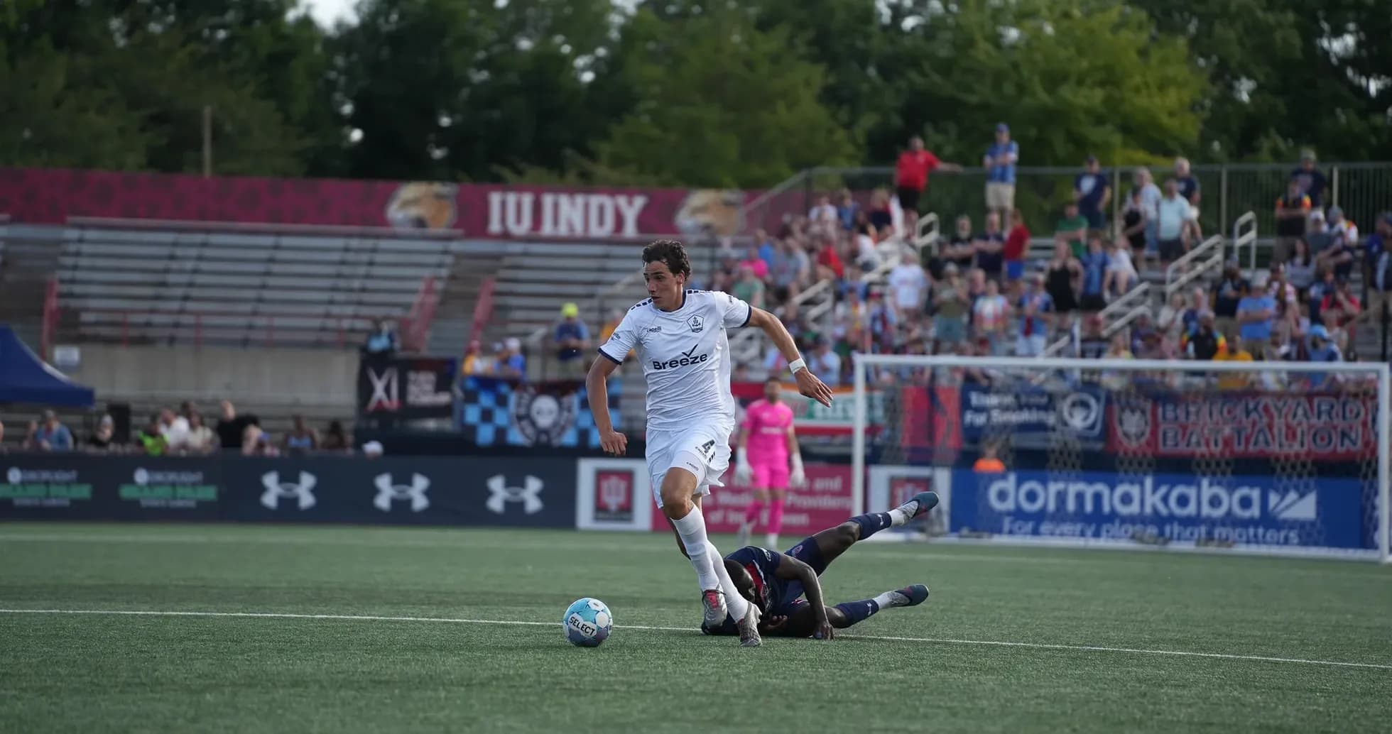 Jugador de Indy Eleven driblando a oponente caído Jugador de Indy Eleven driblando a oponente caído