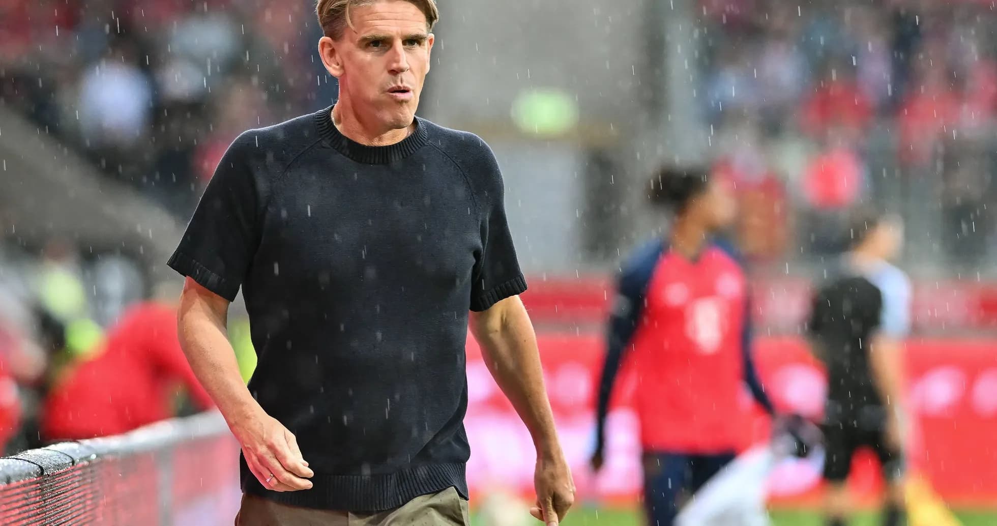 Entrenador caminando bajo la lluvia durante el partido Entrenador caminando bajo la lluvia durante el partido