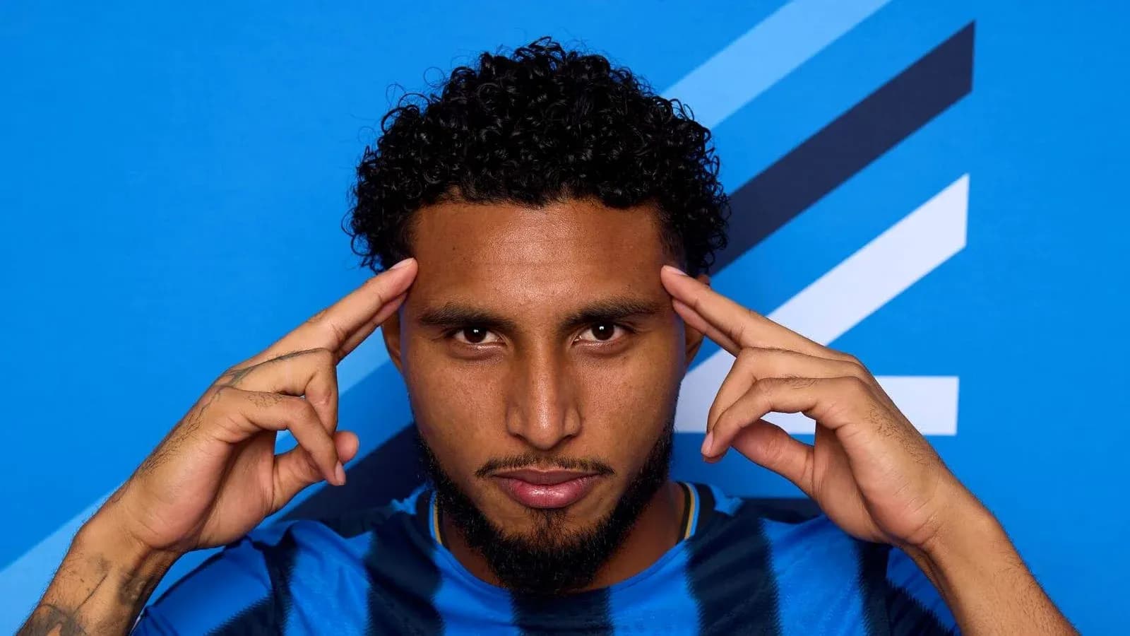 Jugador posando con fondo azul en camiseta deportiva Jugador posando con fondo azul en camiseta deportiva