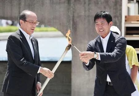 Dos personas encendiendo una antorcha durante ceremonia Dos personas encendiendo una antorcha durante ceremonia