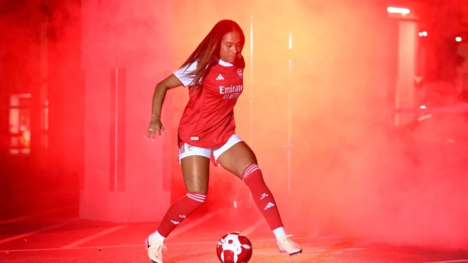 Jugadora de fútbol con balón en ambiente de humo rojo Jugadora de fútbol con balón en ambiente de humo rojo