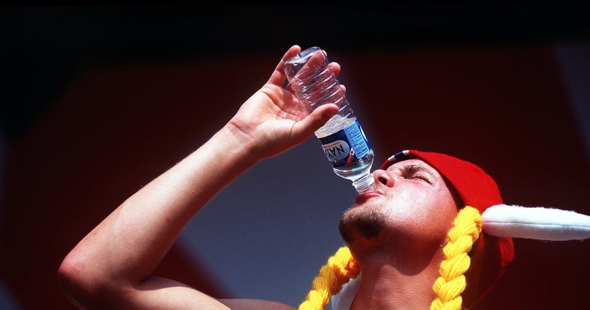 Hombre bebiendo agua de botella con gorra roja Hombre bebiendo agua de botella con gorra roja