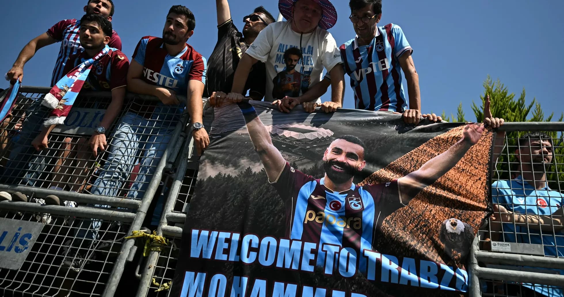 Aficionados sosteniendo un cartel de bienvenida a jugador Aficionados sosteniendo un cartel de bienvenida a jugador