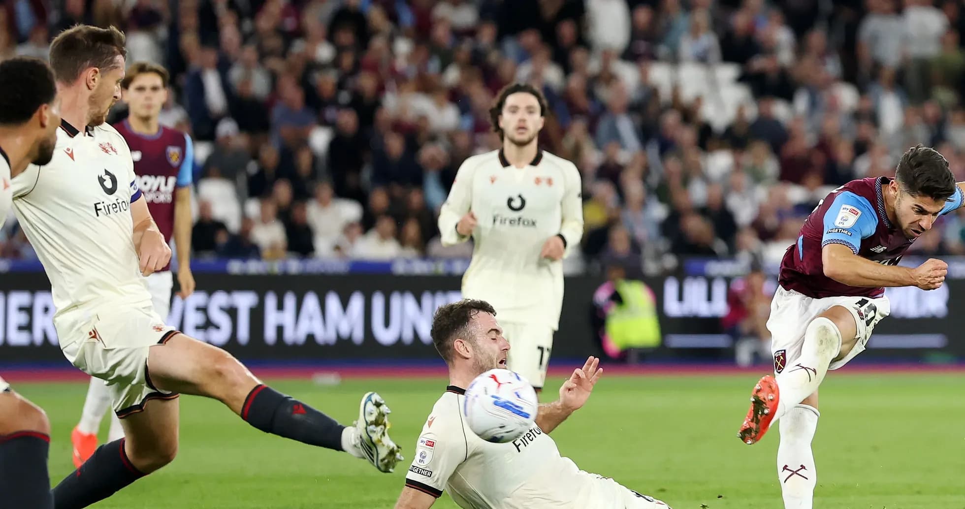 Jugador de West Ham disparando mientras un rival cae Jugador de West Ham disparando mientras un rival cae