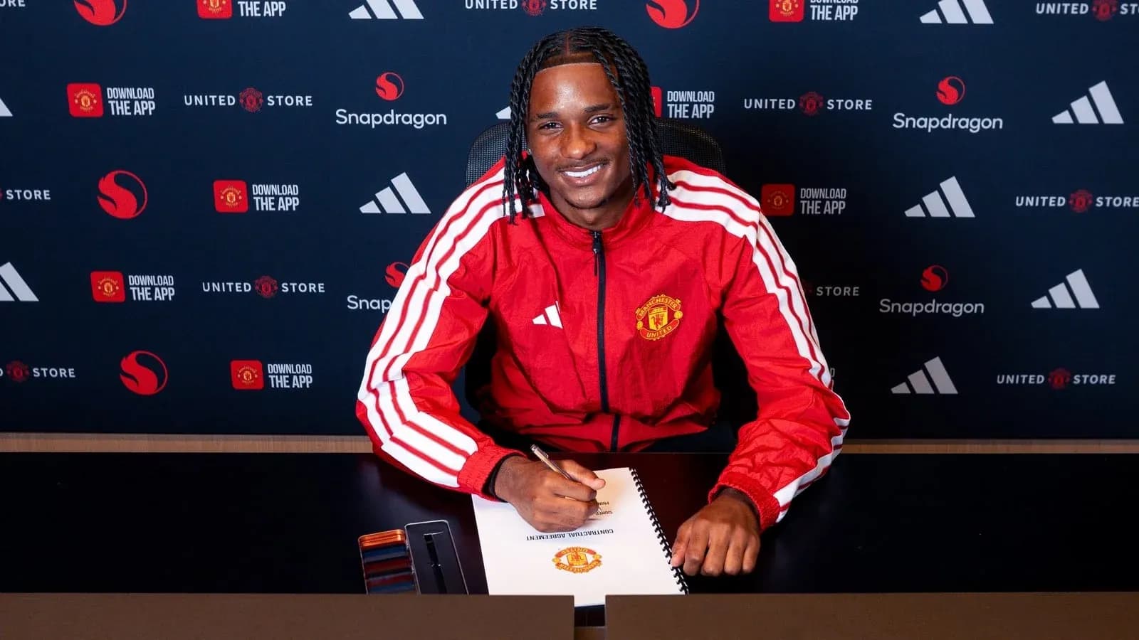 Jugador de Manchester United firmando contrato en mesa Jugador de Manchester United firmando contrato en mesa